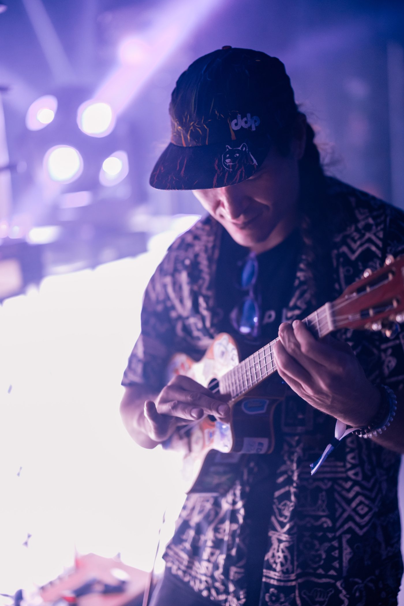 Shaka smiling, playing ukulele in purple light